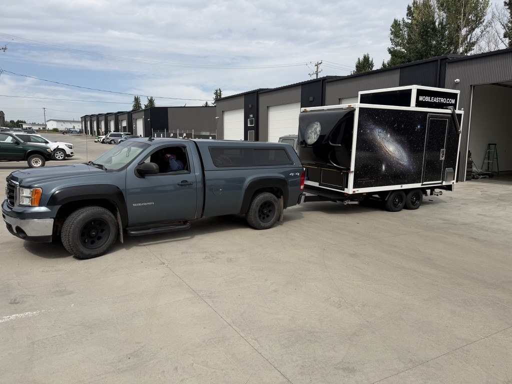 The decaled Mobile Astro trailer hitched to a GMC Sierra pickup, wind deflector open showing the Moon graphic